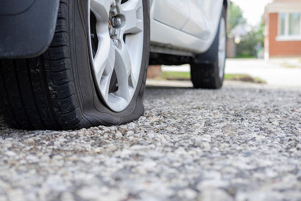 Close up of flat rear tire of white SUV track car vehicle automo TREADNAT Whatshouldyoudowhenyougetaflattire